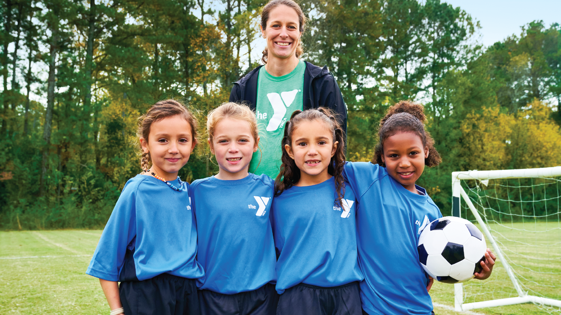 young girl ymca soccer players line up by the soccer goal for a picture