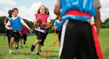 girl running across a flag football field