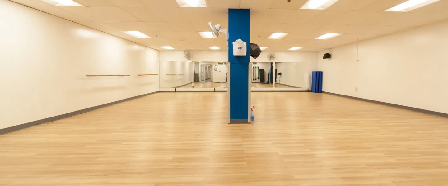 Group exercise room with mirrors on one side. Large, rectangular room with non-slip flooring.