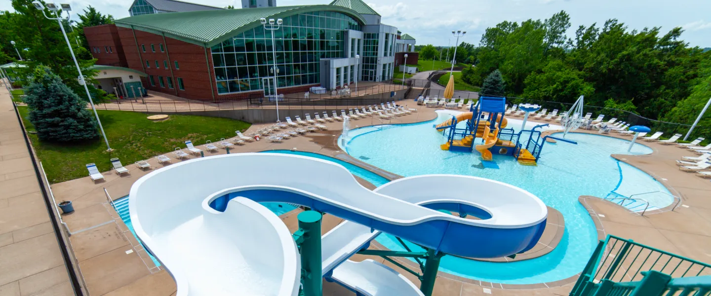 RiverChase YMCA Gym Fenton, MO Outdoor Aquatic Center featuring a water slide, lazy river, zero-depth entry pool, kiddie splash pad and play structure, and lap pool.