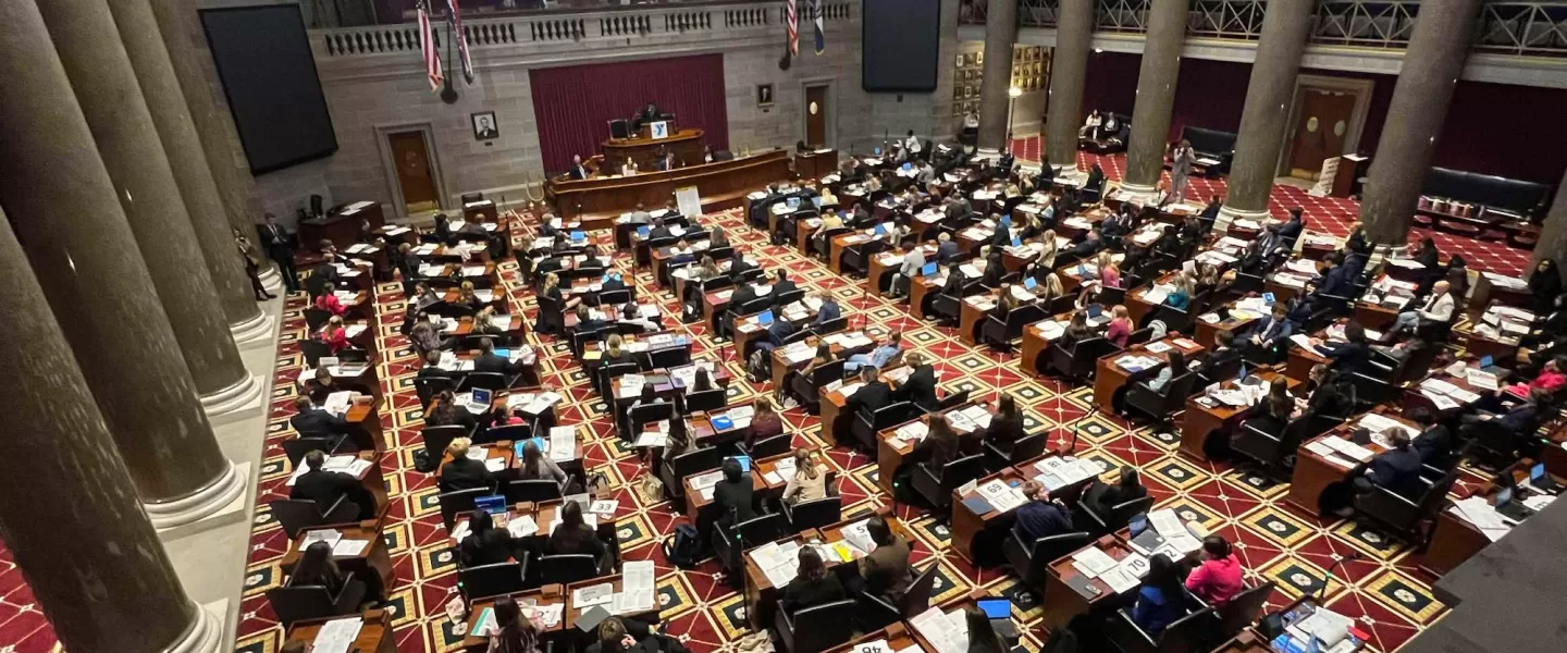 Students in Legislative Session – A diverse group of high school students dressed in business attire sits in a large courthouse floor.