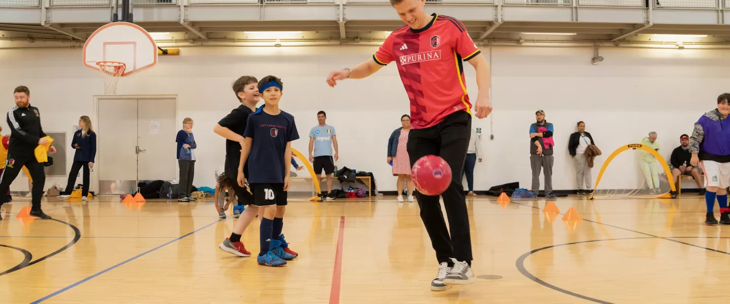 St. Louis CITY SC Defender, Joakim Nilsson, demonstrates a juggling move to YMCA youth, helping them improve their technique.