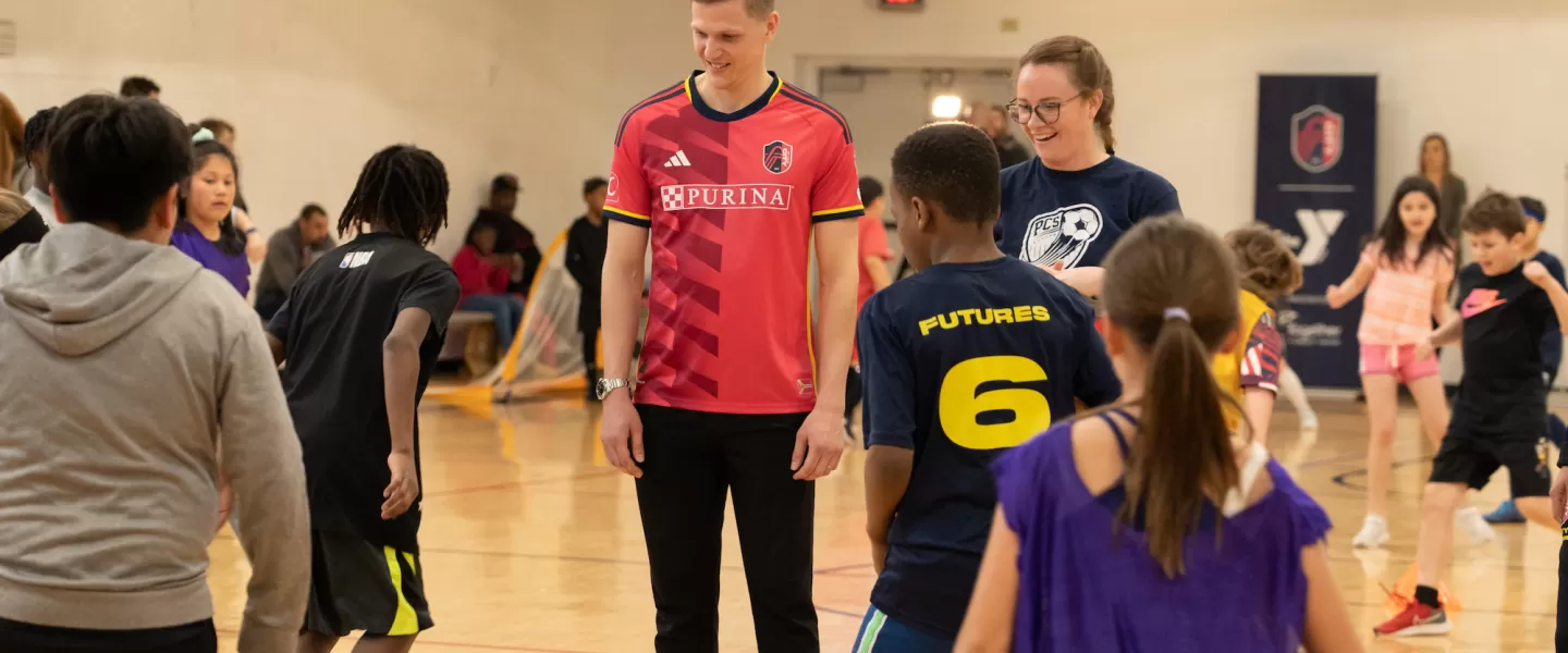 St. Louis CITY SC Defender, Joakim Nilsson, interacts with YMCA youth, offering tips and encouragement during soccer drills at the kickoff event.