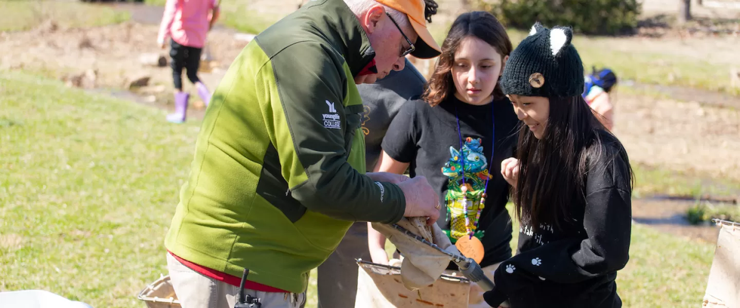 Students collecting water samples from a lake during an Aquatic Ecology session