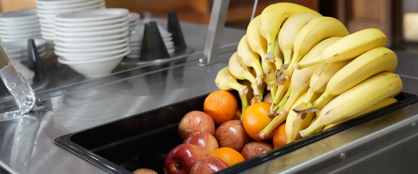 Fresh fruit selection including apples, oranges, and bananas available at each meal
