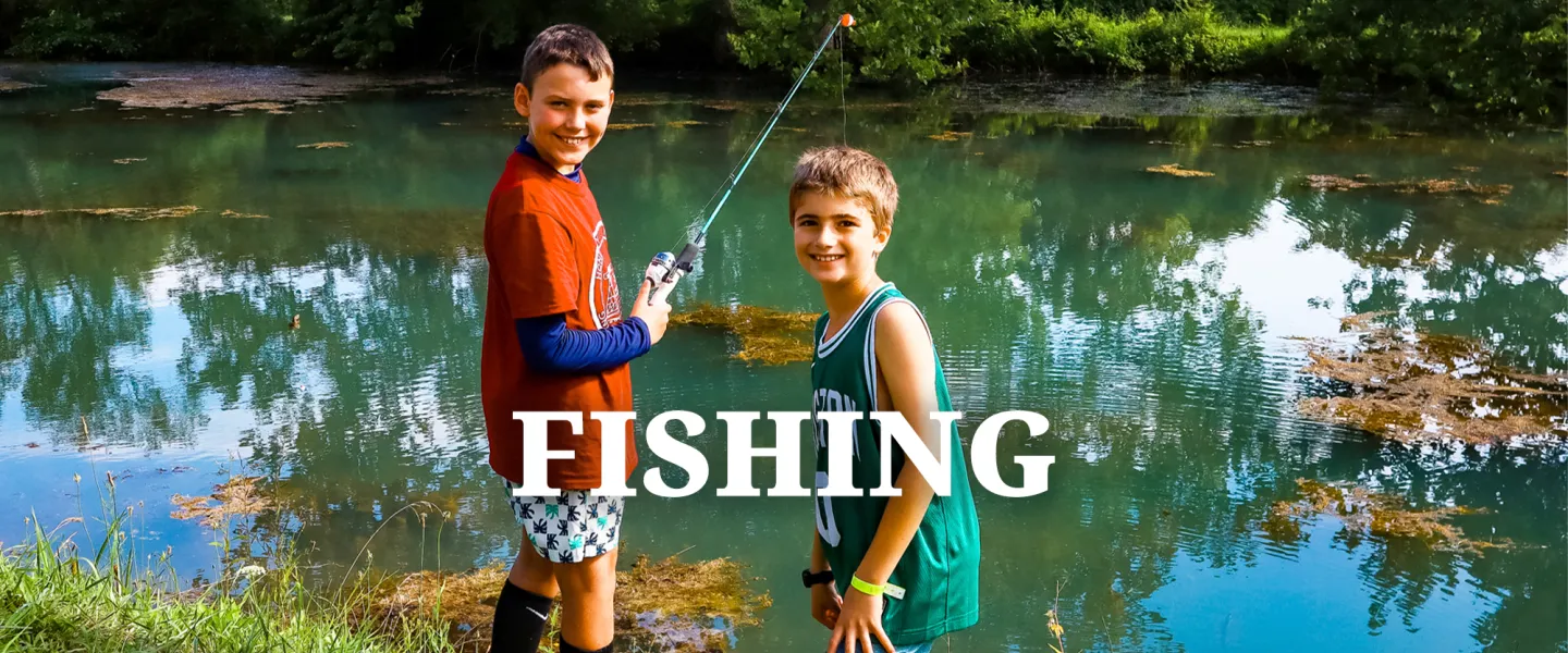 A camper standing on the dock holding a fishing rod, waiting for a catch.