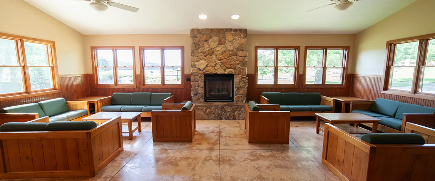 The spacious, sunlit community lounge in a Main Camp cabin, with comfortable couches and a fireplace for campers to socialize.