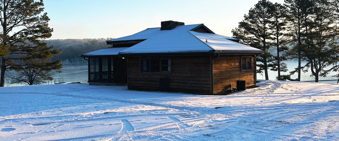 YMCA Trout Lodge Bluff View Cabin covered in winter snow with views of the sun rising over Sunnen Lake