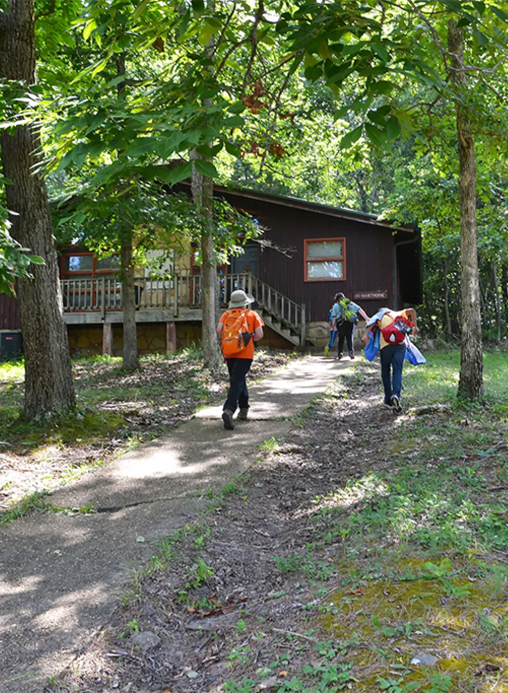 Campers walking towards a YMCA Camp Lakewood Main Camp cabin in the forested woods of Potosi, Missouri