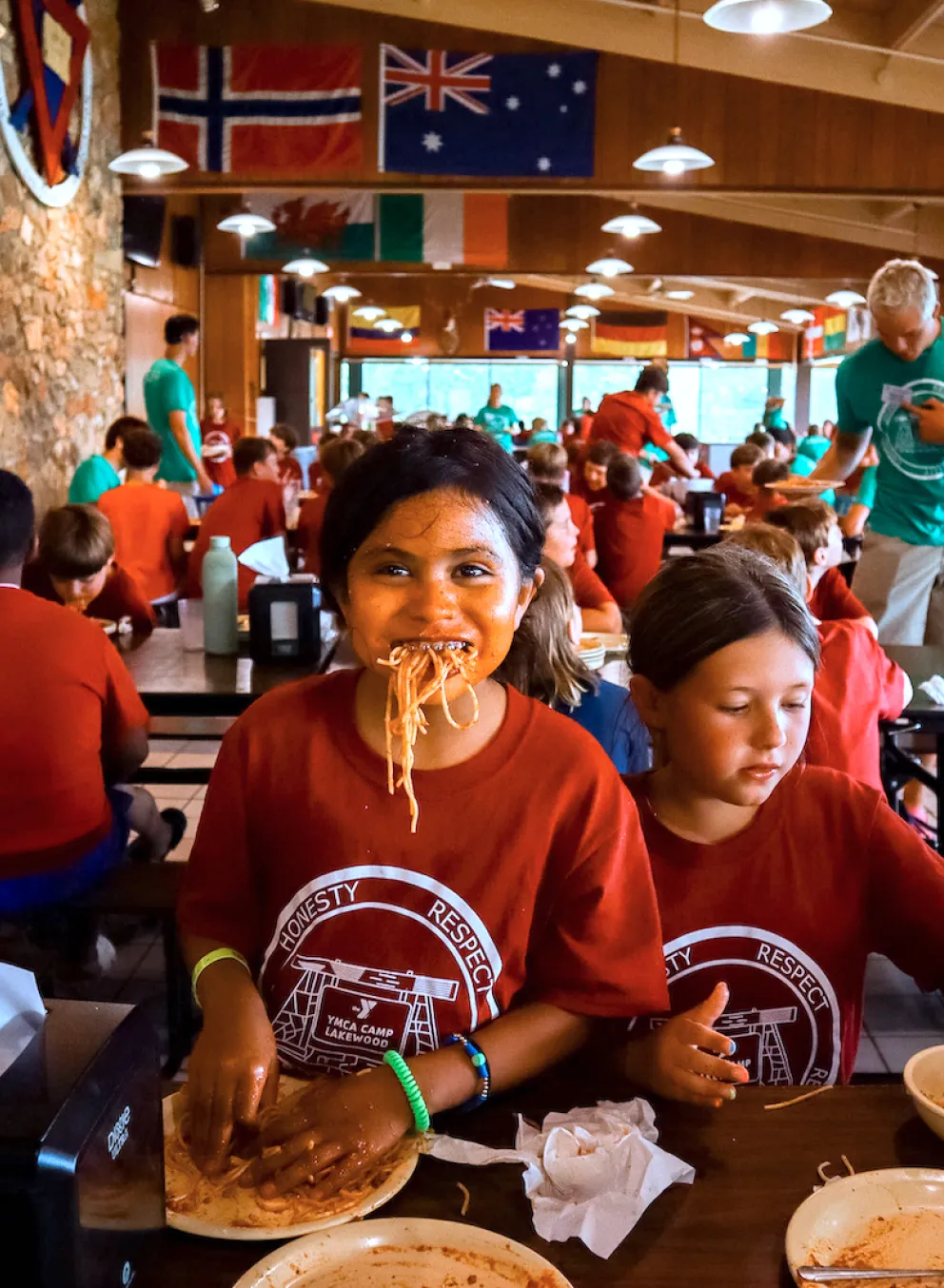 A YMCA Camp Lakewood camper enjoys eating spaghetti with her hands at the famous No Utensils Needed themed dinner.