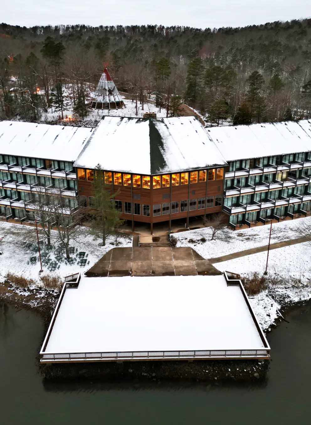 A view of YMCA Trout Lodge room's private patio decks overlooking Sunnen Lake, surrounded by the Ozark Hills forest trees covered in Winter snow.