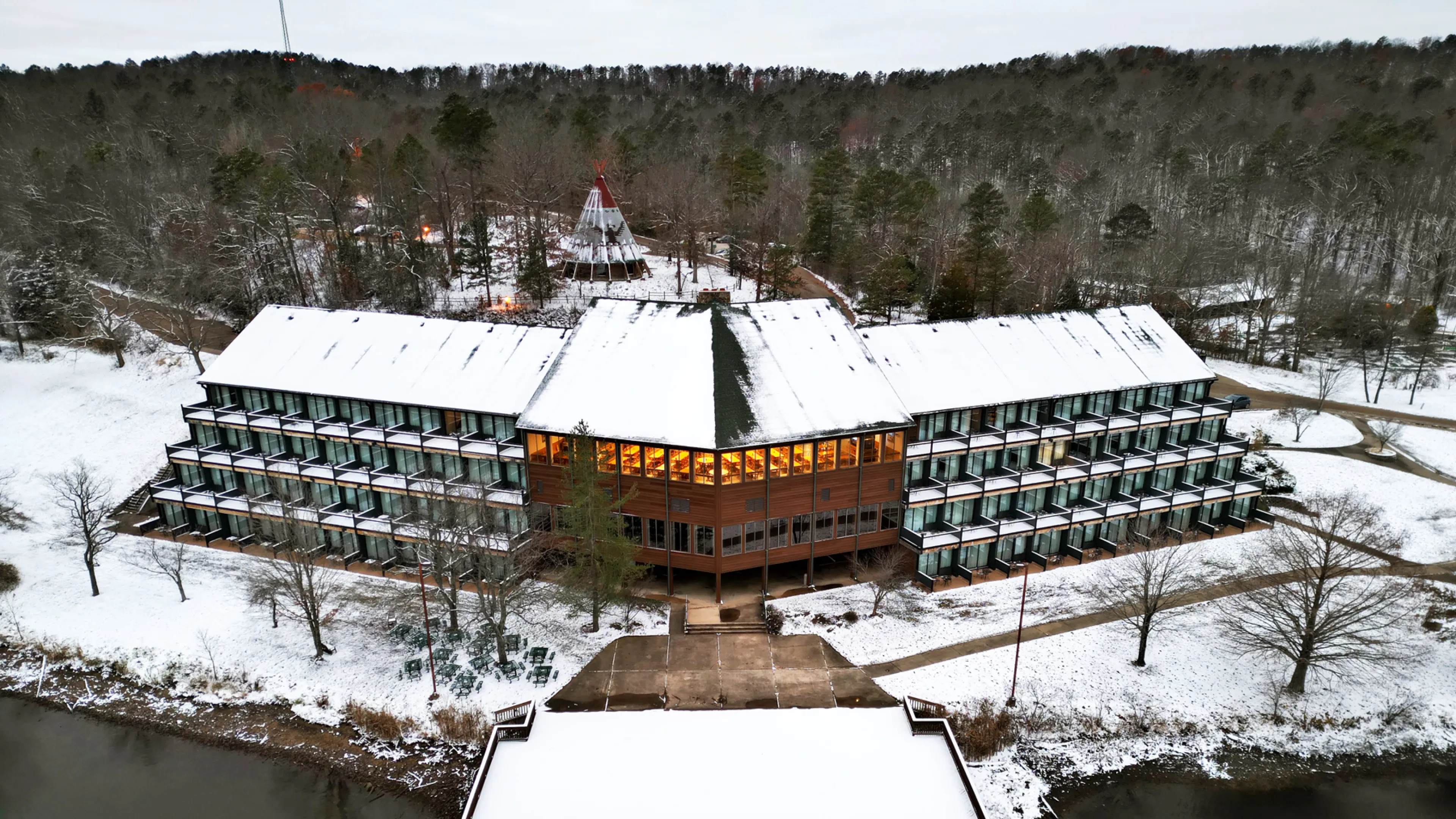 A view of YMCA Trout Lodge room's private patio decks overlooking Sunnen Lake, surrounded by the Ozark Hills forest trees covered in Winter snow.