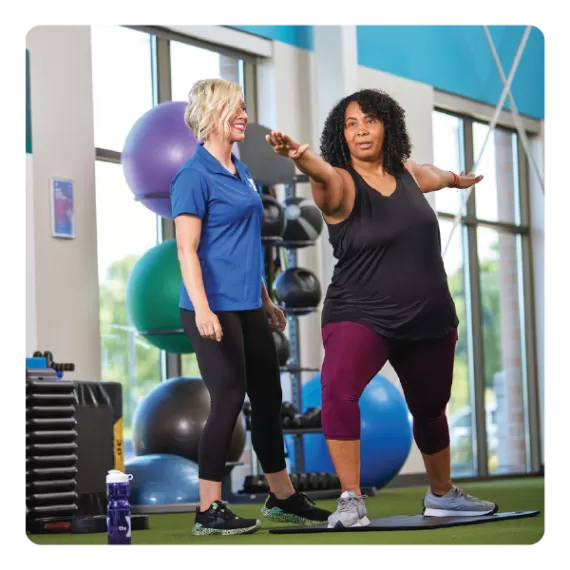 A woman practices yoga with the help of a Y Staff Member personal trainer