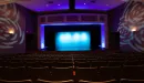 Thumbnail: Theater with rows of seating facing stage. Stage lit with side lights. Dim theater lighting throughout room.