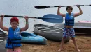 Thumbnail: Young boys holding kayak paddles above their heads