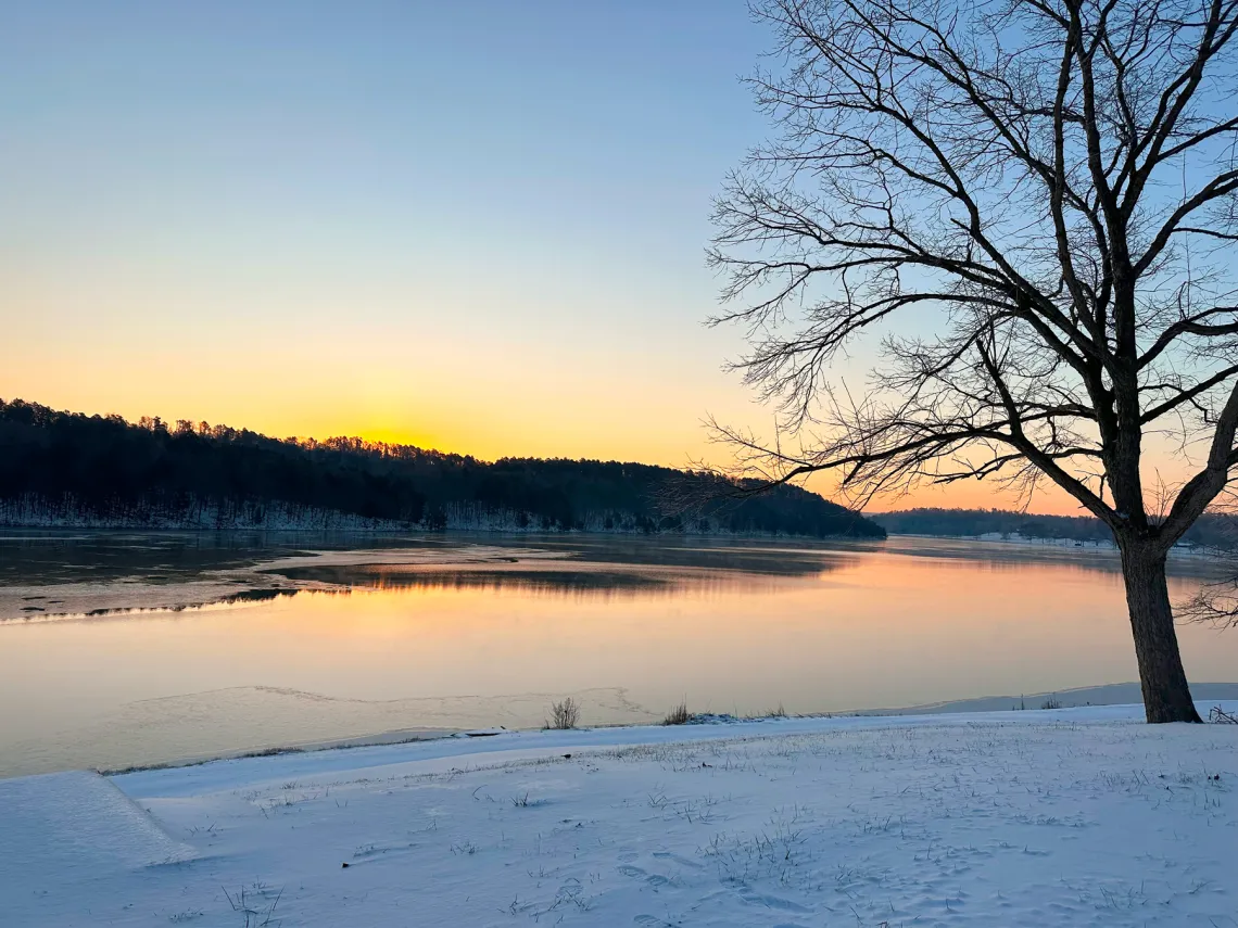 YMCA Trout Lodge Frozen Winter Sunnen Lake with the sunset setting behind the Ozark Hills forest trees.