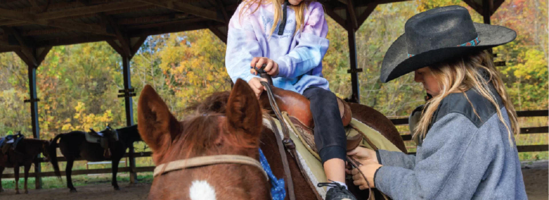 a girl gets saddled up to go horseback riding at ymca trout lodge
